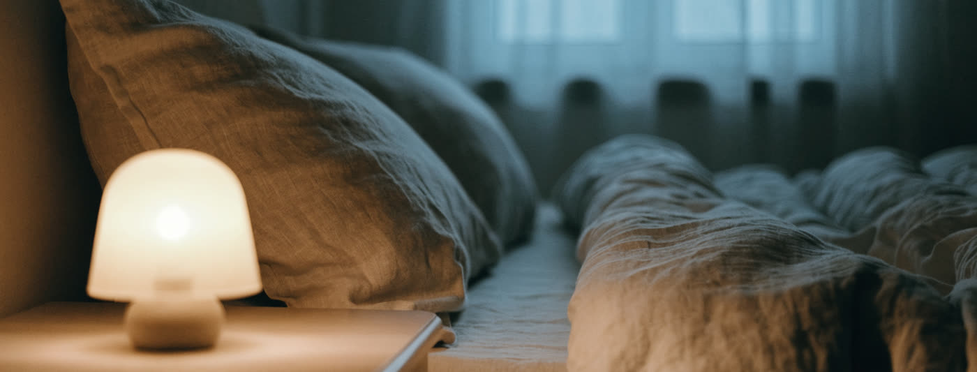 A dim, calm bedroom at night with soft lamplight