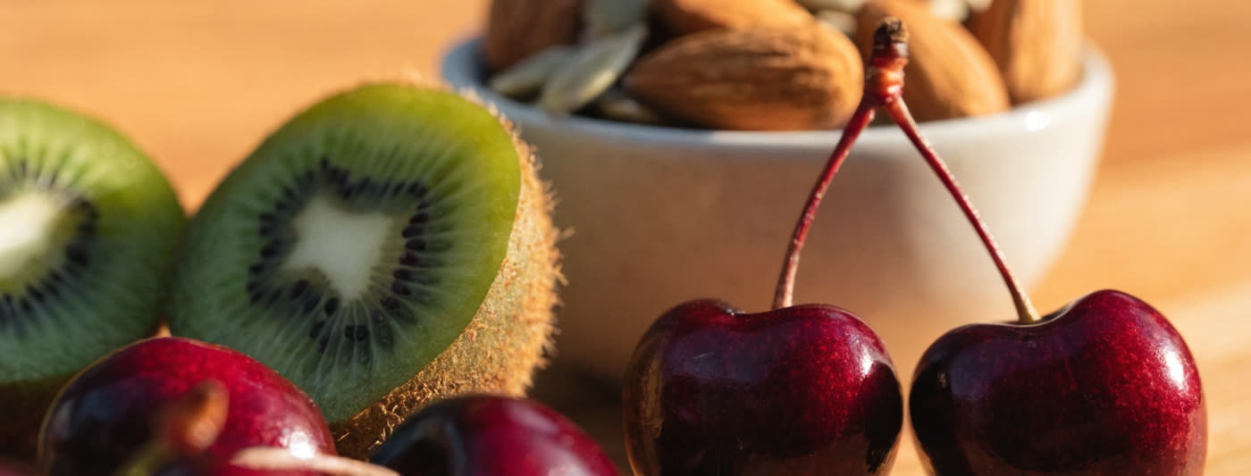 Tart cherries, kiwifruit and other foods linked to better sleep, arranged on a table in evening light