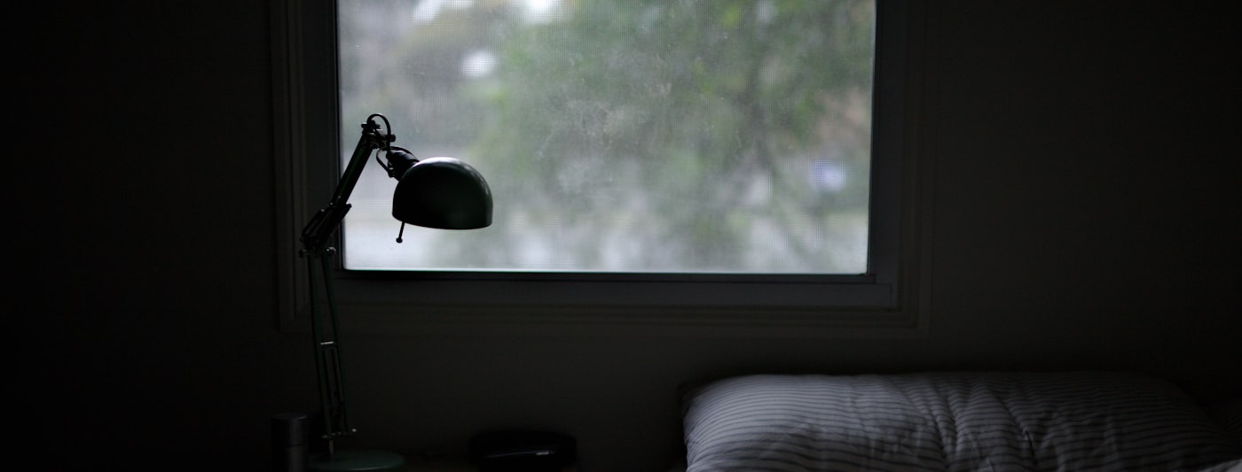 A bed beside a softly lit bedside lamp